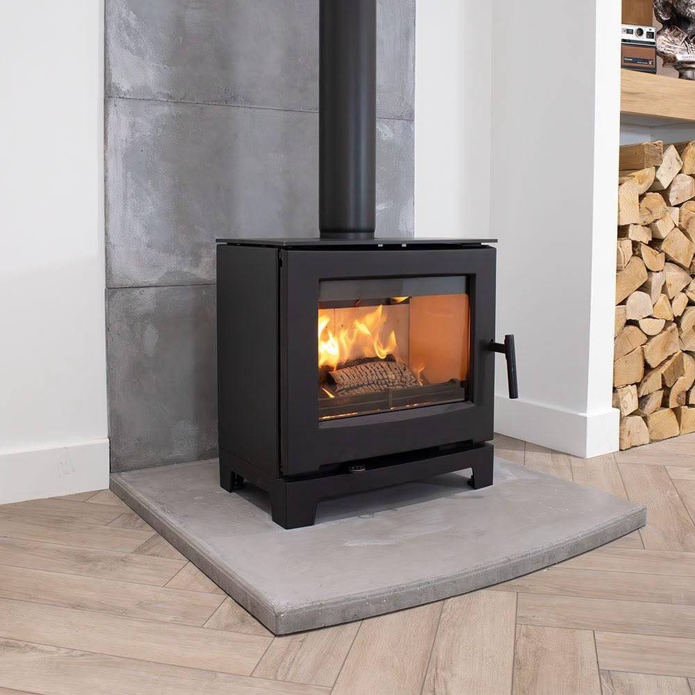 Modern wood burner on a polished concrete hearth beside a log store