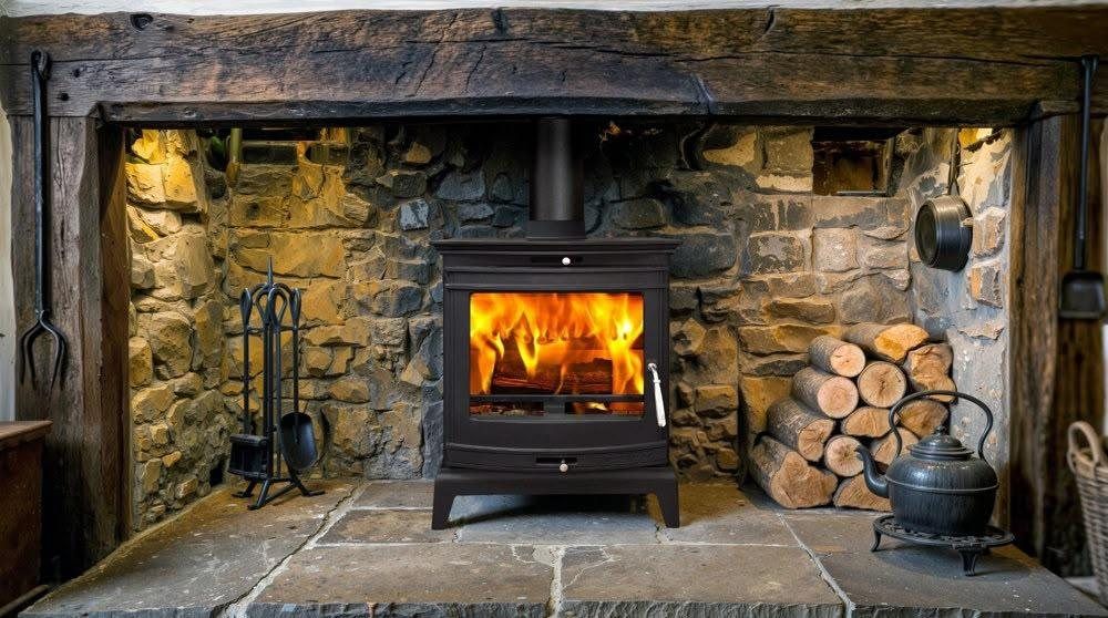 Cast iron wood burner in a traditional stone inglenook fireplace with log pile